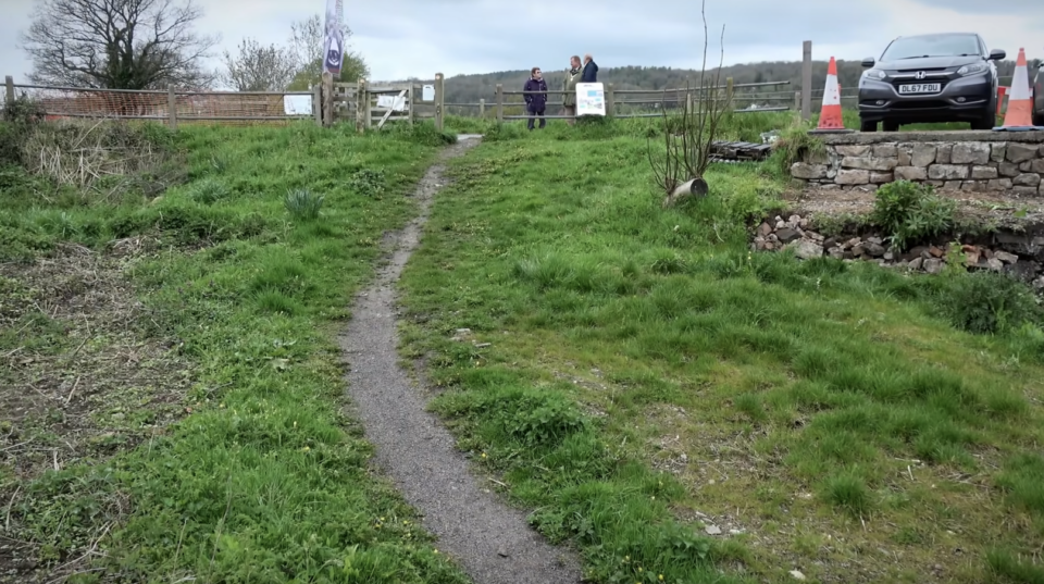 A grassy bank that needs a bridge cut into it for the canal to go under.